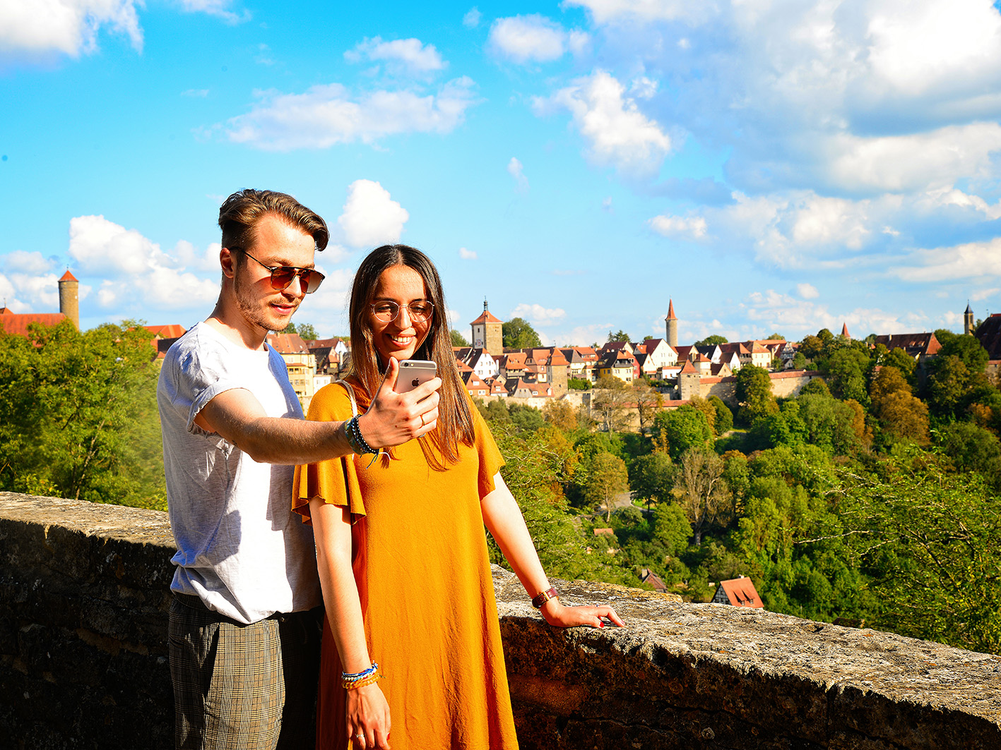 Der romantischestrasse-reiseblog zeigt ein junges Paar, das vor der Kulisse von Rothenburg ein Selfie macht